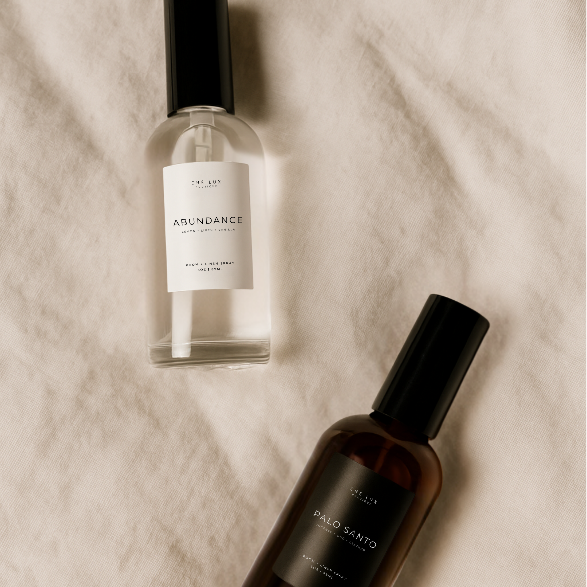 Two bottles of 'Abundance' on a textured beige surface