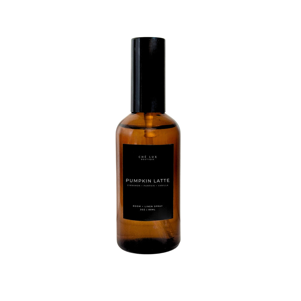 Ché Lux Boutique amber glass room and linen spray bottle with a black label featuring PUMPKIN LATTE and CINNAMON + PUMPKIN + VANILLA scent notes, topped with a black spray nozzle