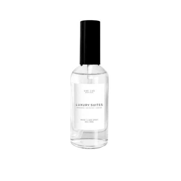 Ché Lux Boutique Luxury Suites Room Linen Spray in a clear glass bottle with black cap and white label listing Mandarin White Tea Jasmine scents 3oz 89ml