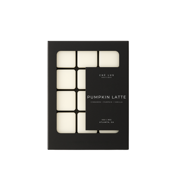 Product photography of a Che Lux Boutique Pumpkin Latte wax melt box from Atlanta GA, showcasing a black package with a distinctive cutout revealing eight pale square melts and its cinnamon pumpkin vanilla fragrance profile
