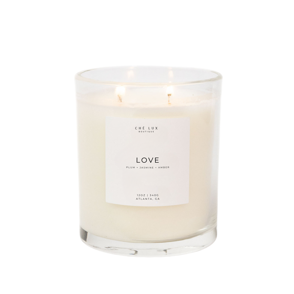 Ché Lux Boutique two-wick LOVE candle in a clear glass container featuring plum jasmine and amber scent from Atlanta GA