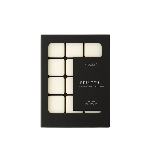 Product photography by CHE LUX BOUTIQUE showing a black box of Fruitful wax melts from Atlanta GA, featuring eight visible off-white rectangular melts and fig brown sugar sea salt fragrance notes